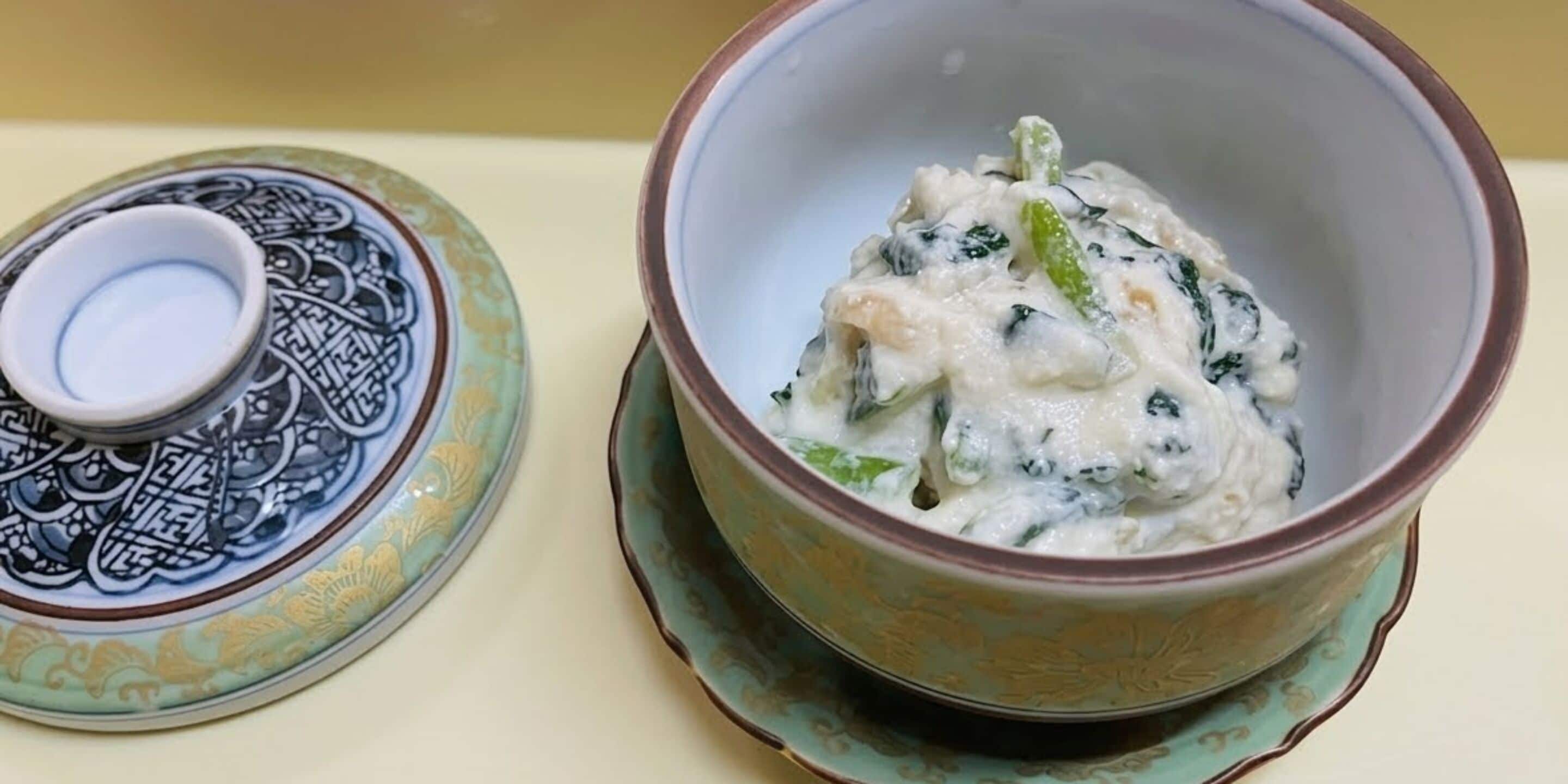 A bowl of creamy soup with spinach on a ceramic plate.