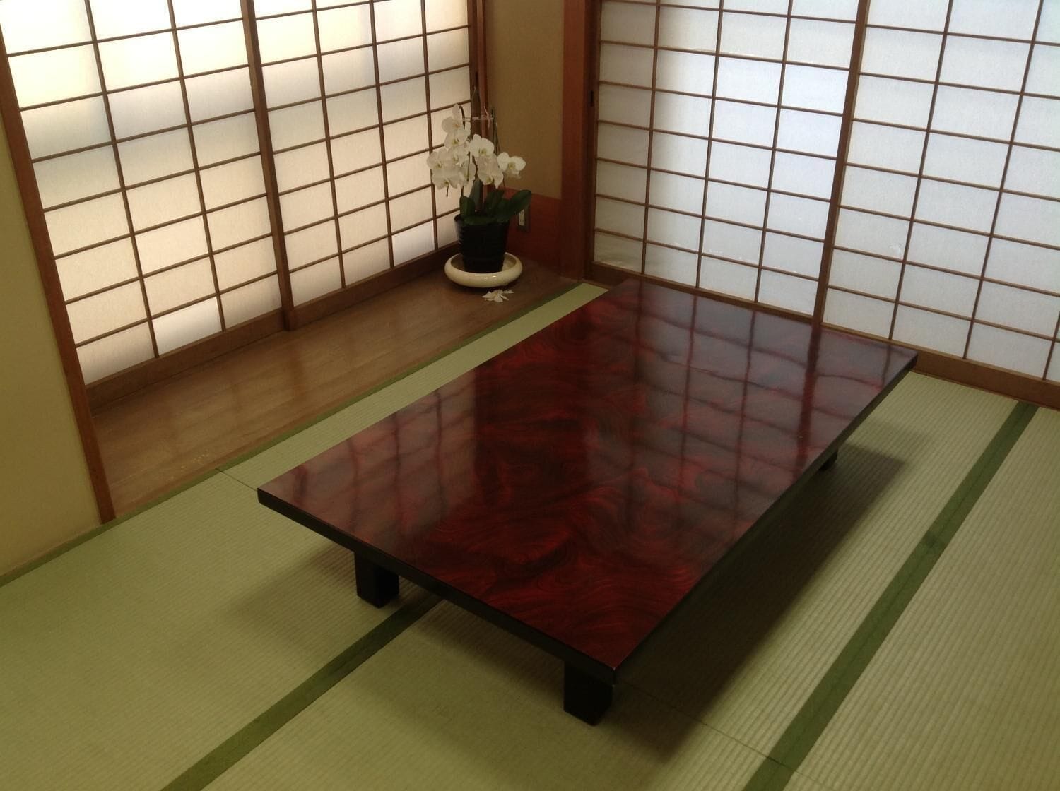 A tatami mat room with a low table and a small potted plant.
