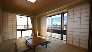 Una habitación japonesa tradicional con suelo de tatami, una mesa de madera baja y puertas correderas shoji.