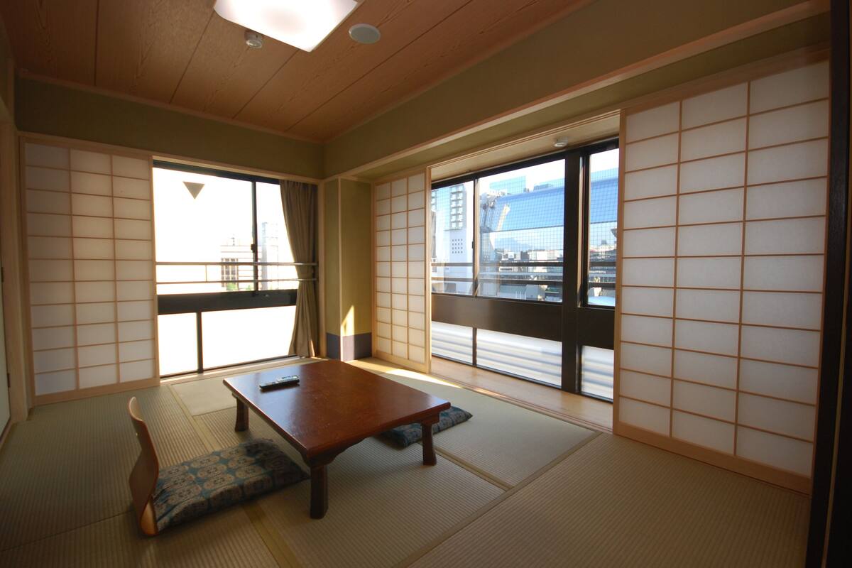 A traditional Japanese room with tatami flooring, a low wooden table, and shoji screens.