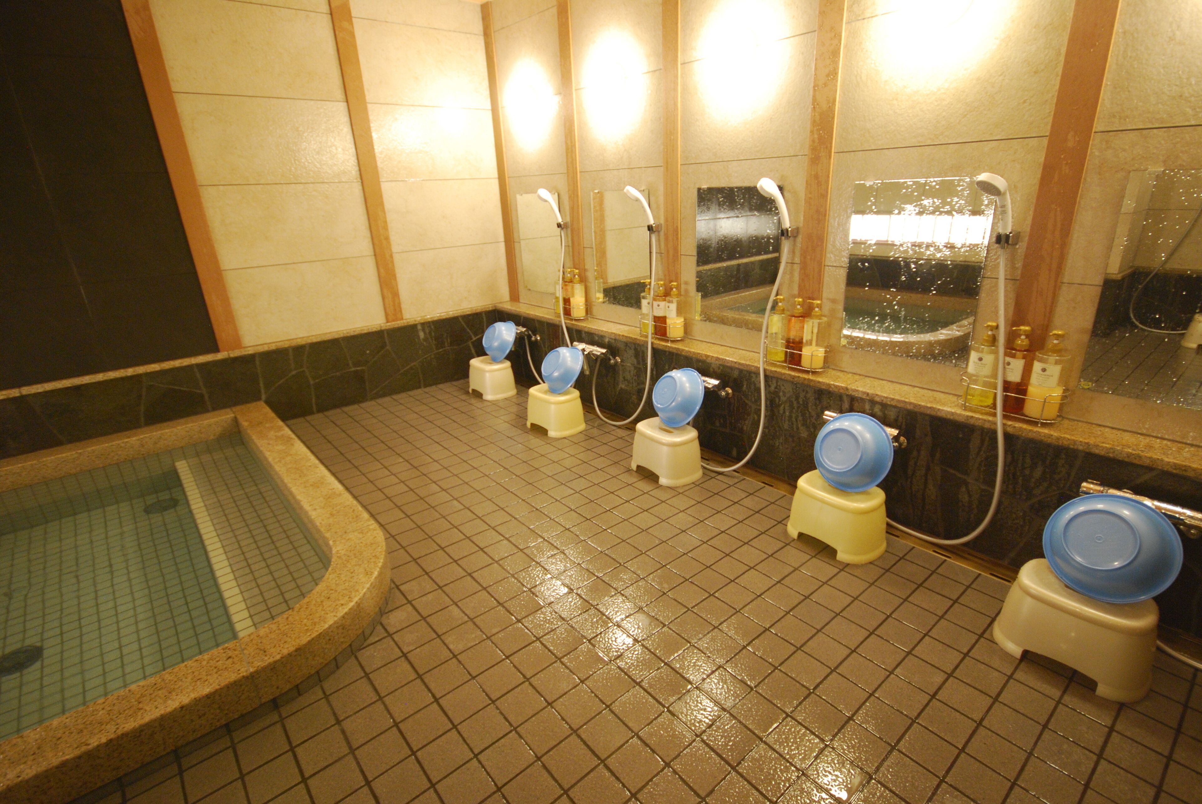 A public restroom with multiple sinks, a large mirror, and a tiled floor.