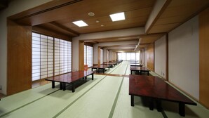 Una habitación japonesa tradicional con suelo de tatami, puertas correderas de madera y una mesa larga con bancos.