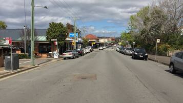 A street view with parked cars, a bus stop, and a building with a sign that reads "Greville."