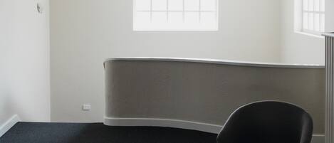 A modern room with a curved bench, a single chair, and a small table.