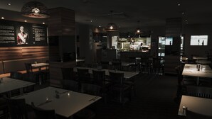 Un restaurant à la lumière tamisée, avec des tables et des chaises disposées pour accueillir les clients.