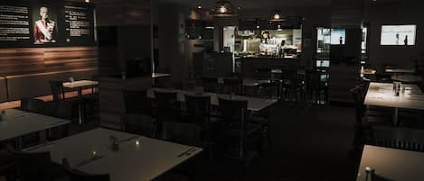 A dimly lit restaurant with tables and chairs arranged for dining.