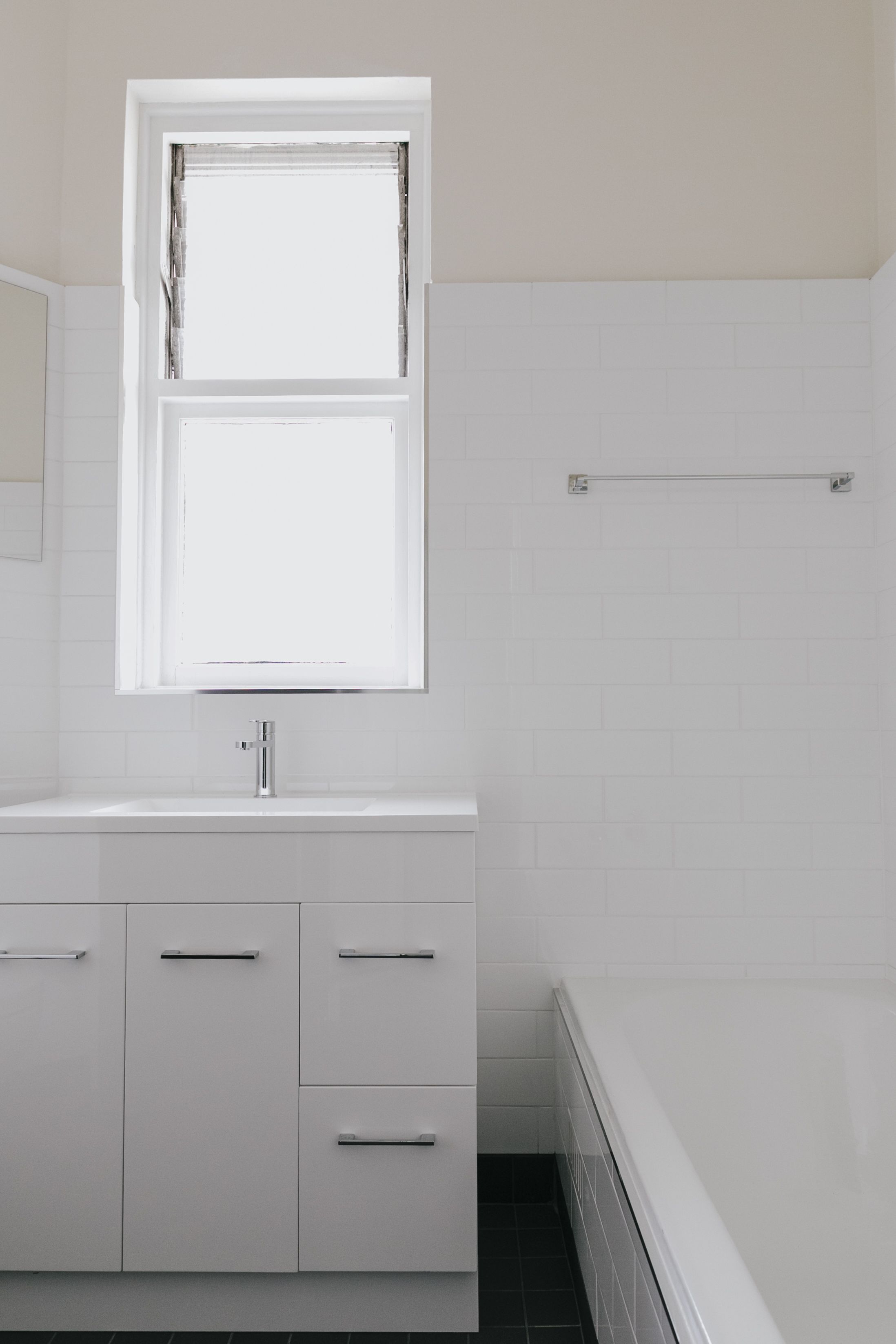 Un bagno con un lavandino bianco, una finestra e un porta asciugamani.