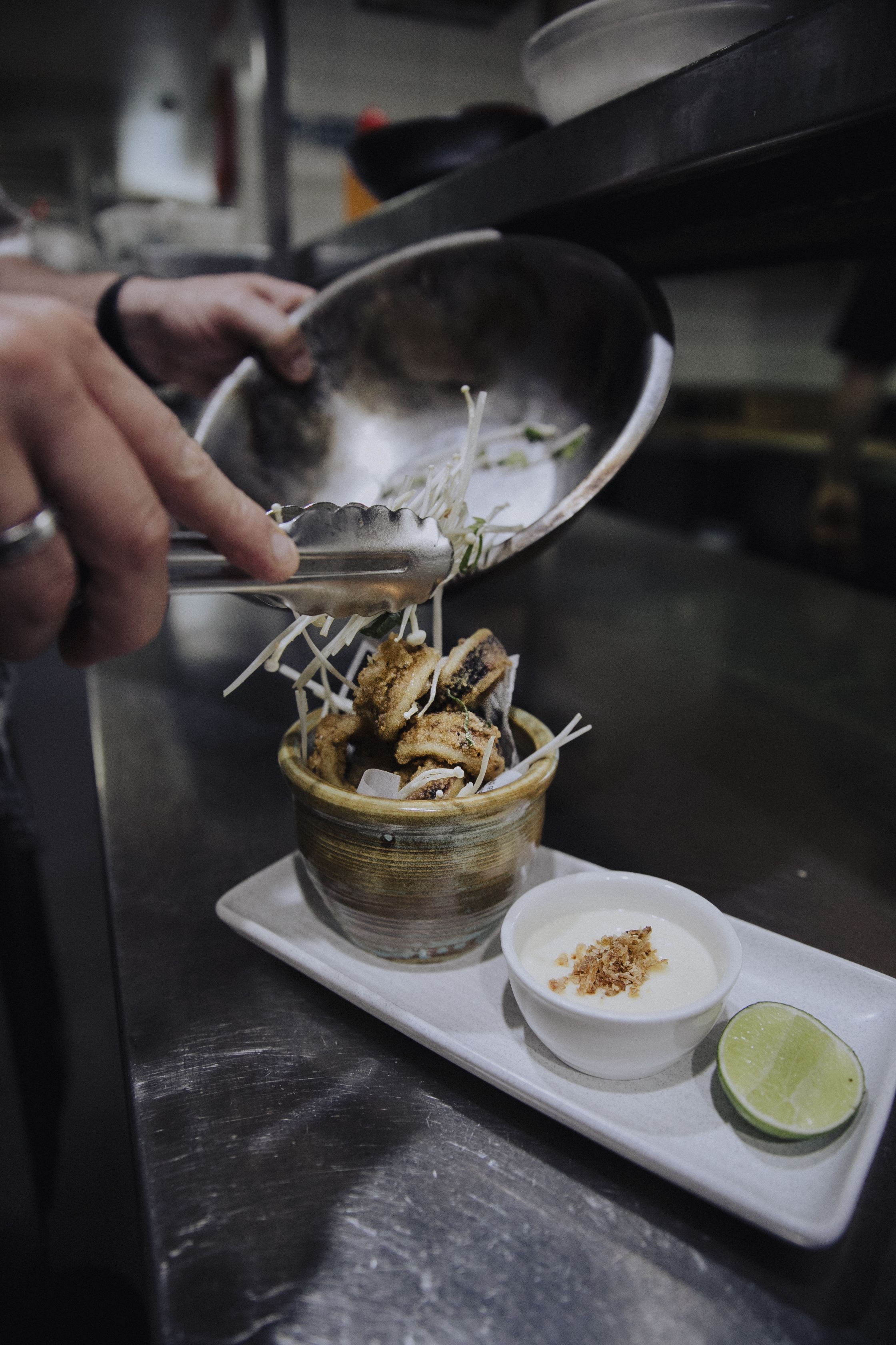 A person serving food from a bowl using tongs.