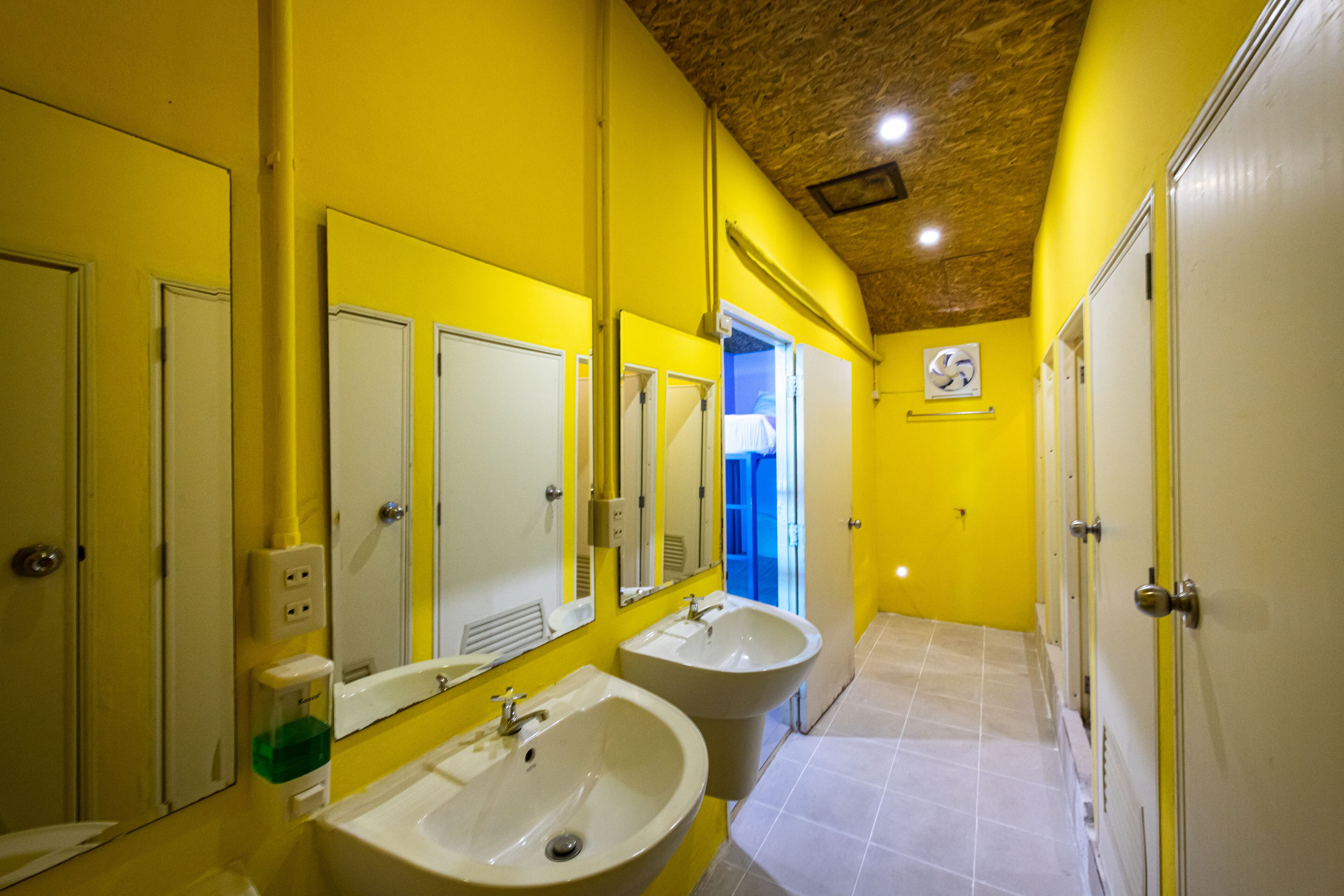 A bathroom with yellow walls, two sinks, and mirrors.