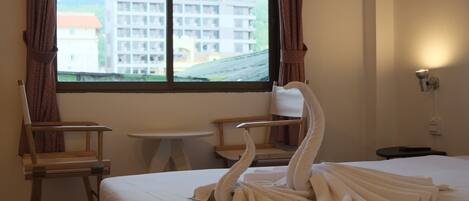 Een hotelkamer met een bed, een tafeltje, twee stoelen en een raam met gordijnen.