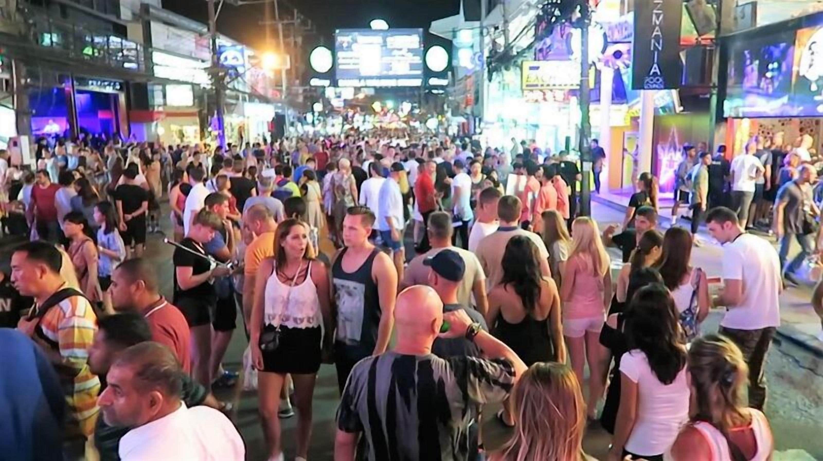 A crowded street scene with people walking and standing.