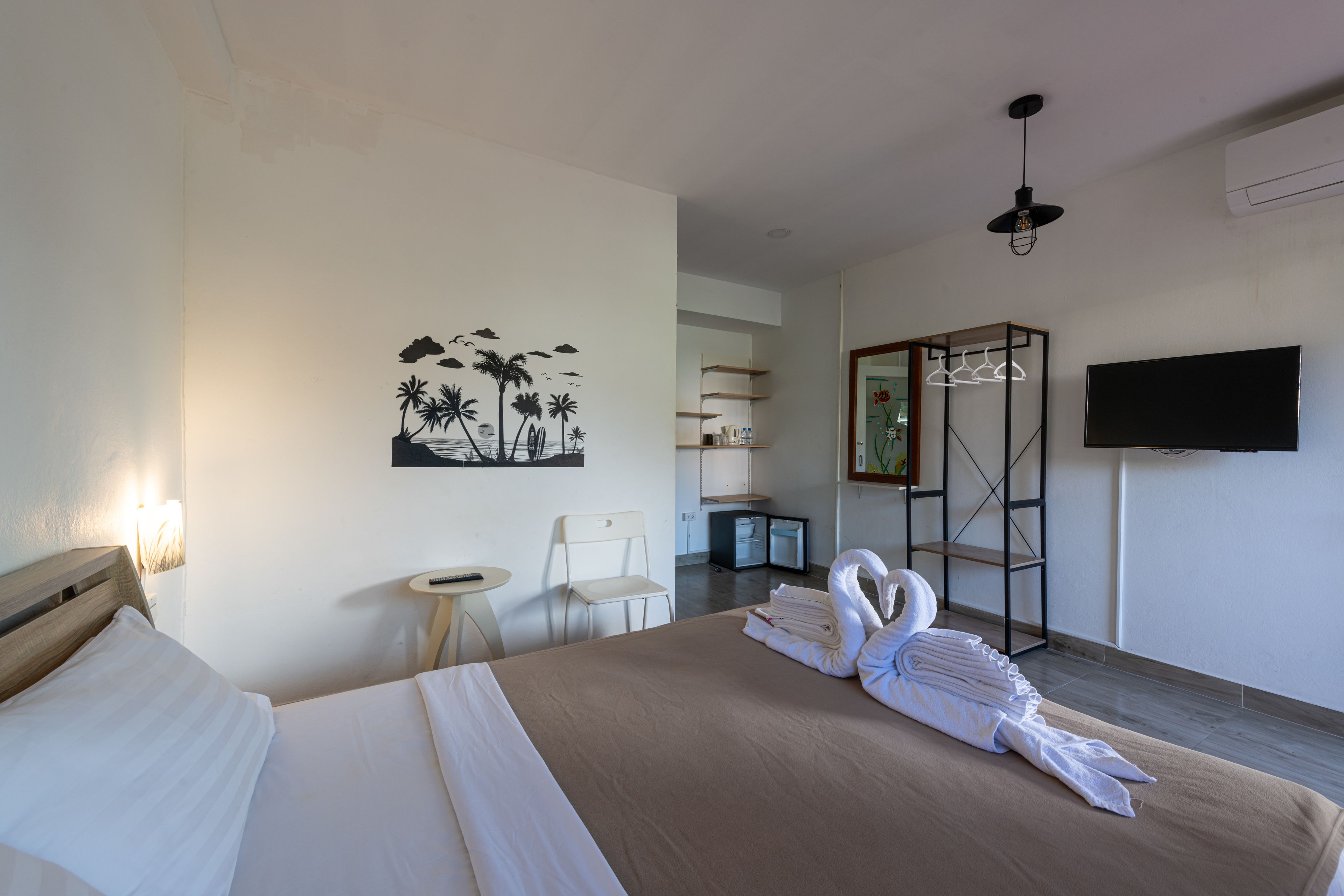 A hotel room with a bed, a desk, a chair, a TV, and a wall art piece.