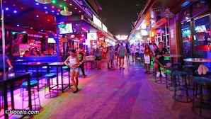 Eine belebte Bar mit Neonreklame und Tischen.