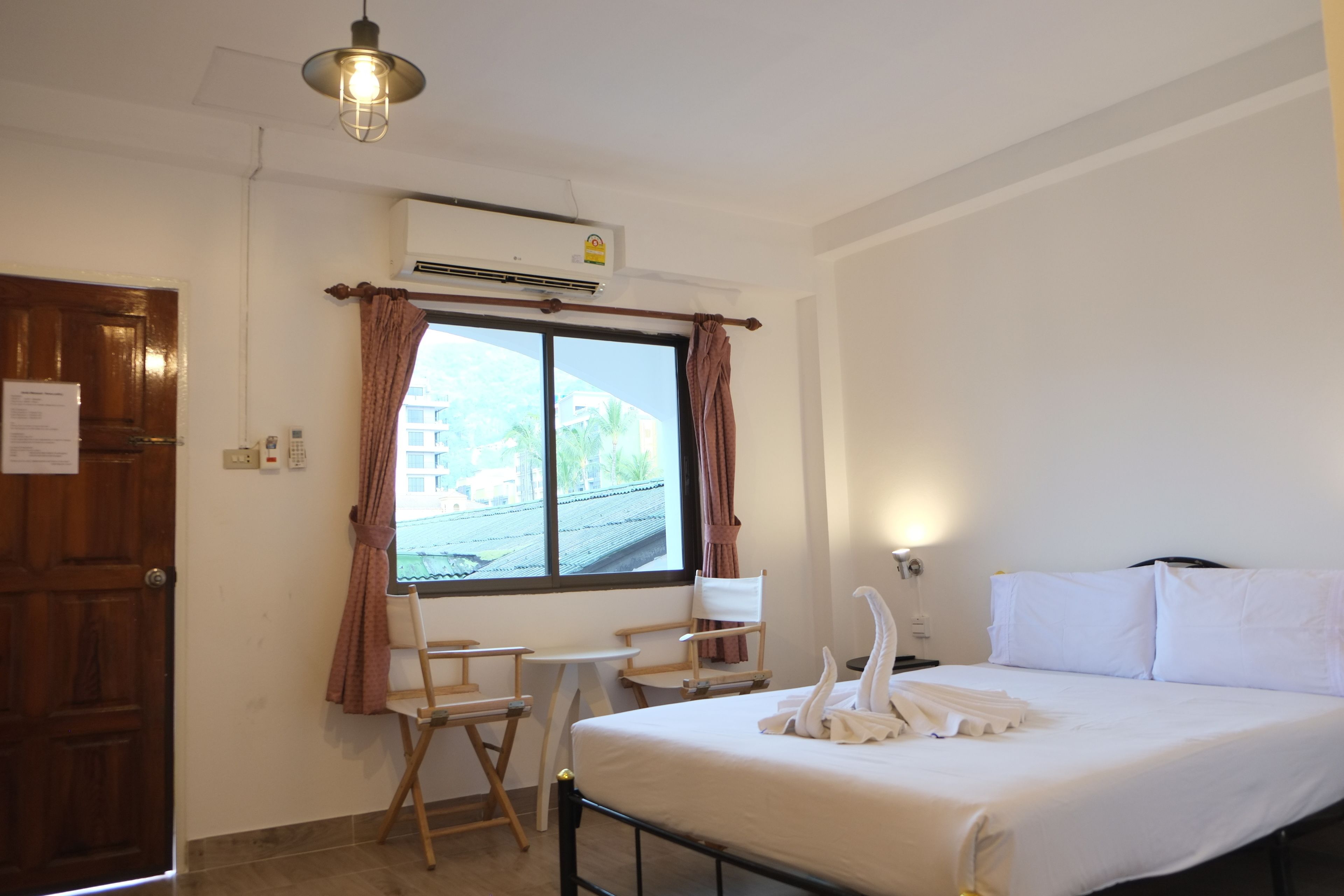 Una habitación de hotel con cama, escritorio, silla y ventana con cortinas.