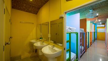 A bathroom with two sinks and mirrors, a wooden ceiling, and a hallway with colorful bunk beds.