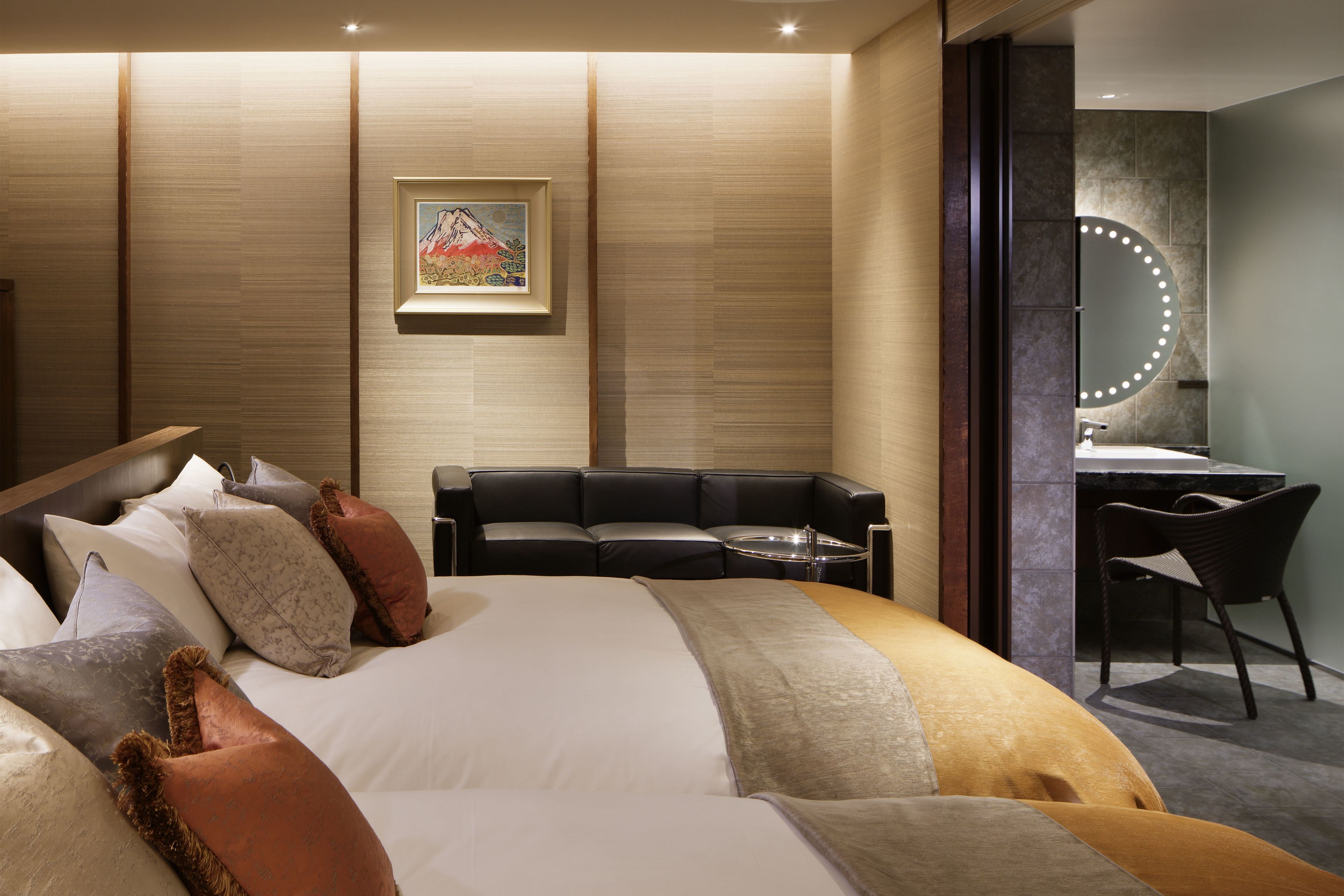 Una habitación de hotel moderna con una cama grande, un sofá, un escritorio y un espejo con luces.