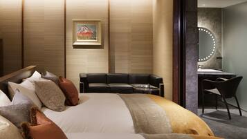 Una habitación de hotel moderna con una cama grande, un sofá, un escritorio y un espejo con luces.