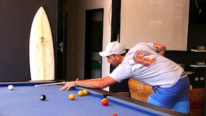 A pool table with balls and a surfboard in the background. - Mooloolaba Backpackers (Mooloolaba)