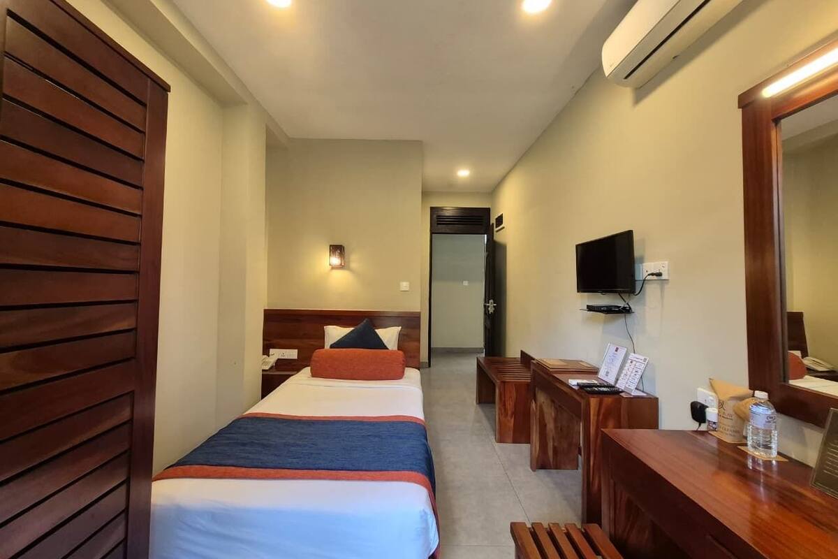 Een hotelkamer met twee bedden, een bureau, een stoel, een televisie en een spiegel.