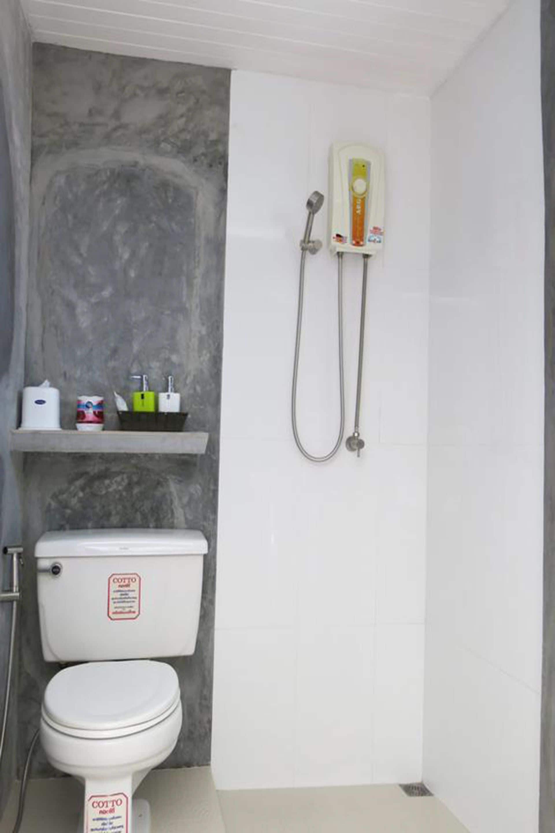 Une salle de bain équipée de toilettes, d’une douche et d’une étagère où sont rangés les articles de toilette.