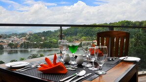 Une table dressée pour le dîner, avec vue sur un lac et sur le paysage urbain.