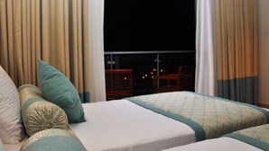 Une chambre d’hôtel avec deux lits, des rideaux de couleur beige et une vue sur le ciel nocturne.
