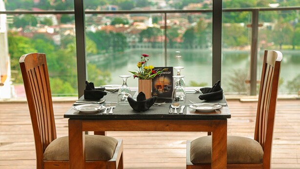 Une table dressée pour un dîner à deux, avec vue sur un lac et des bâtiments en arrière-plan.