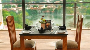 A dining table set for two with a view of a lake and buildings in the background. - Oak Ray Heritage Hotel (Kandy)