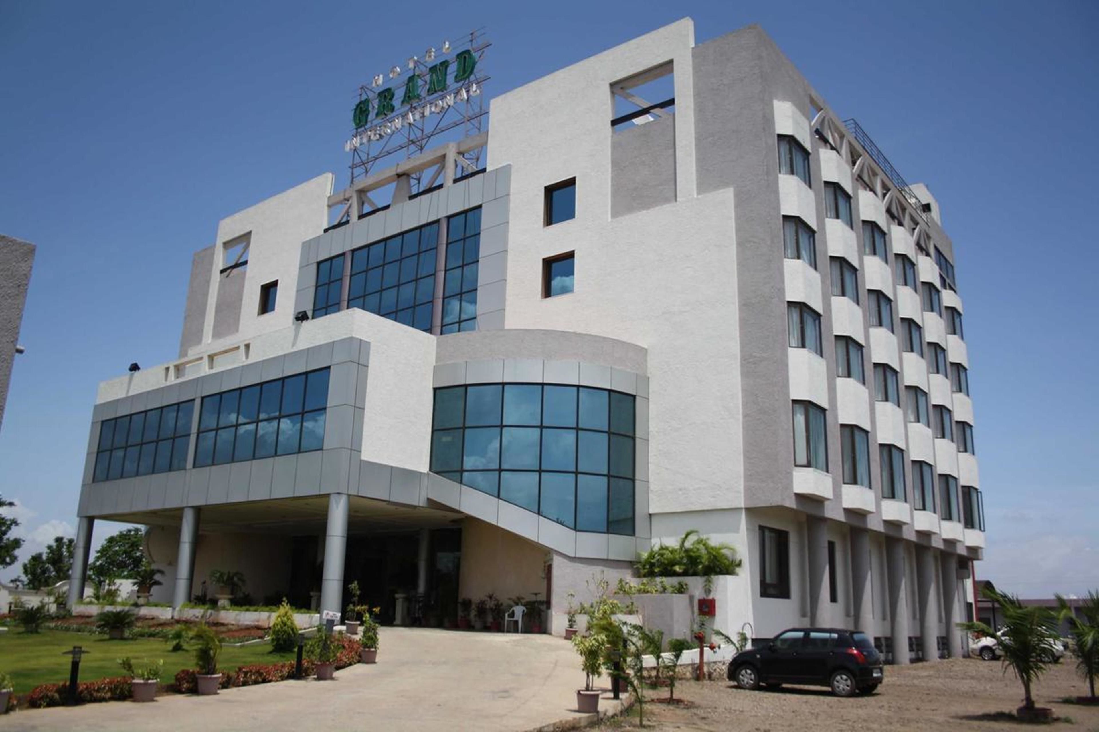 A modern building with a prominent sign at the top, large windows, and a parking area in front.