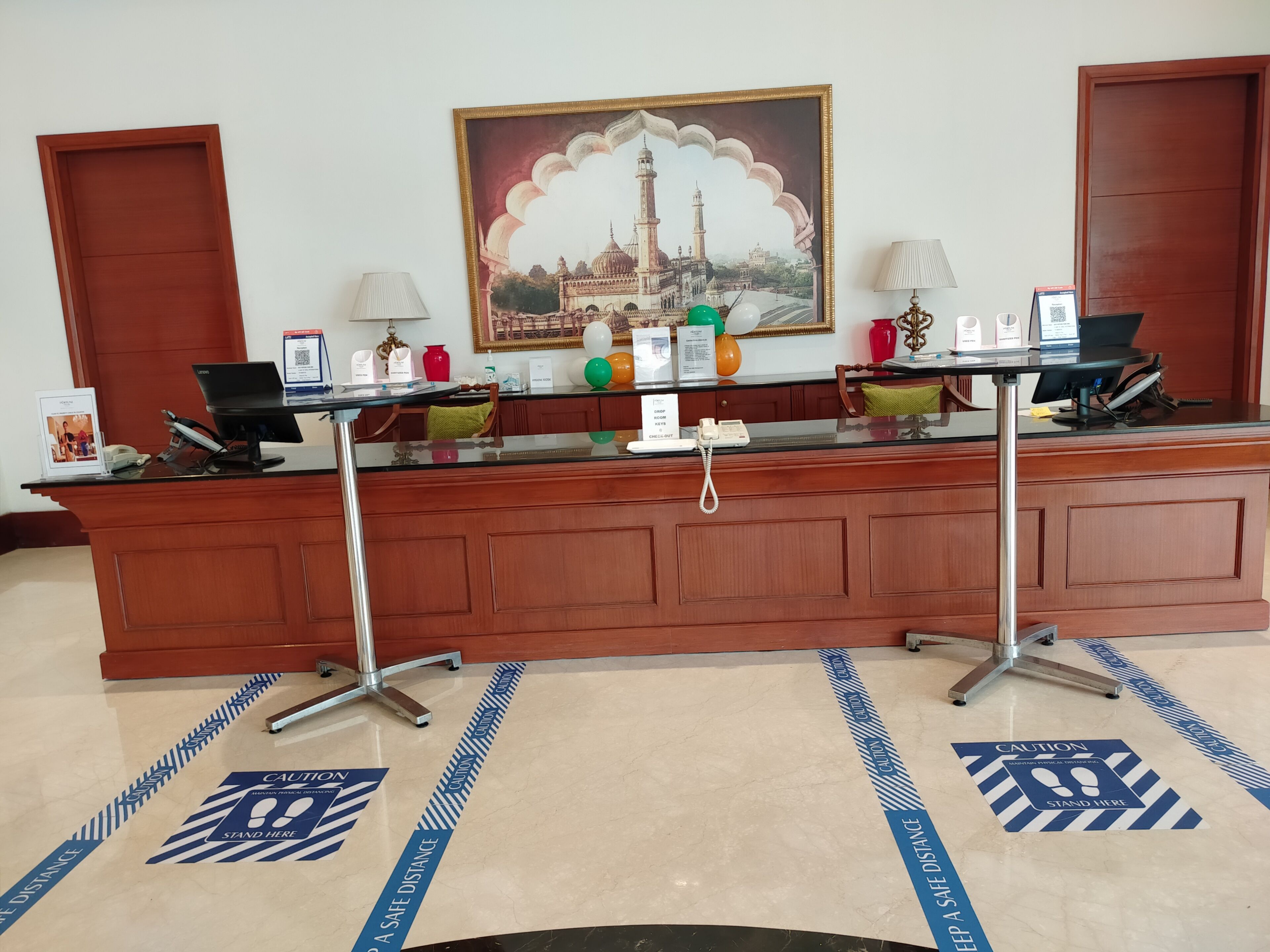A reception desk with a framed painting, a phone, and a computer.