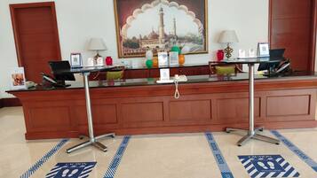 A reception desk with a framed painting, a phone, and a computer.