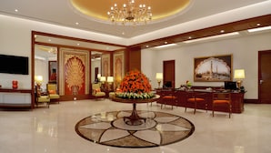 A lobby with a round table, chairs, a chandelier, and a reception desk.