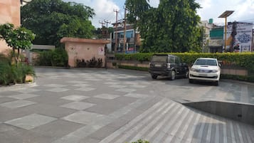 Un estacionamiento con dos coches, un edificio con letreros y follaje.