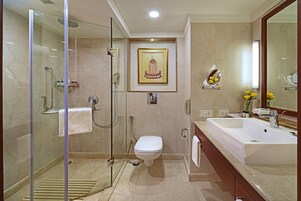 Un baño moderno con ducha de vidrio, inodoro blanco y un lavamanos grande con espejo.