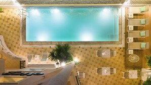 A modern indoor pool with a clear view of the water, a lounge area with seating, and a wooden wall design. - Eliza Hotel by Panel Hospitality (Dio-Olympos)