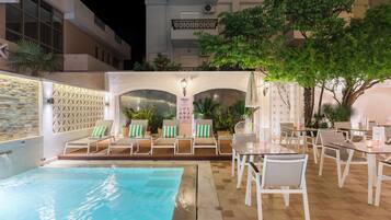 Relax by the pool surrounded by lush greenery and comfortable lounge chairs.