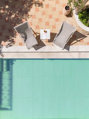 Una piscina al aire libre, sombrillas, tumbonas