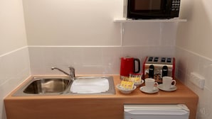 A kitchenette with a stainless steel sink, a red coffee maker, a toaster, and two white cups on a wooden countertop. - Millicent Motel (Millicent)