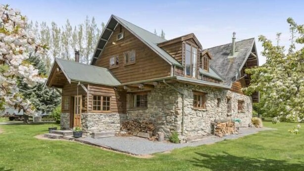 A log cabin with a stone foundation, a sloped roof, and a wooden exterior. - Galaxy Lounge (Burkes Pass)