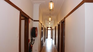 A long, narrow hallway with wooden trim and a wooden floor. - Guildford Hotel (Guildford)