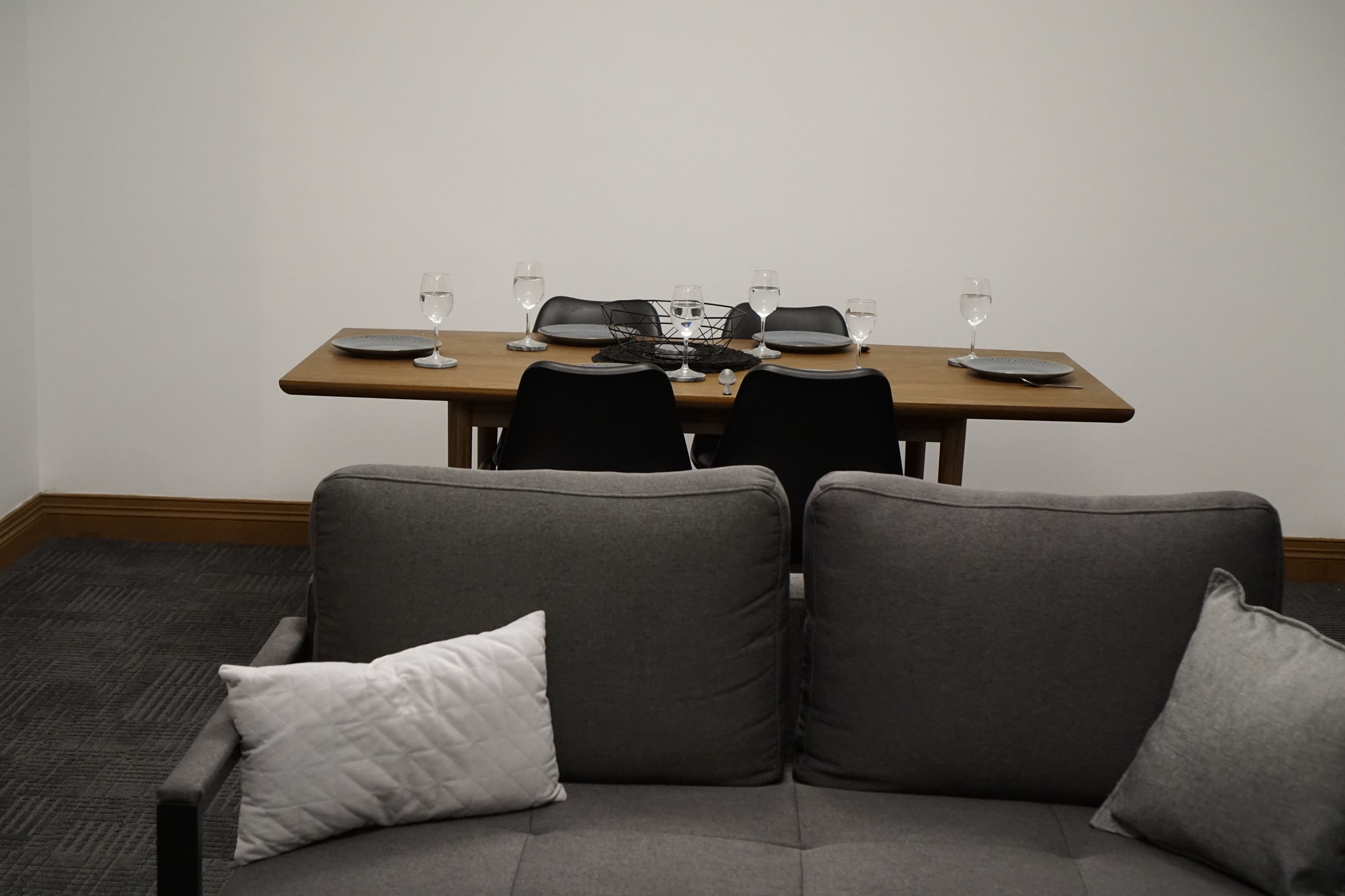 A conference room with a table set for four, including plates, glasses, and a laptop.
