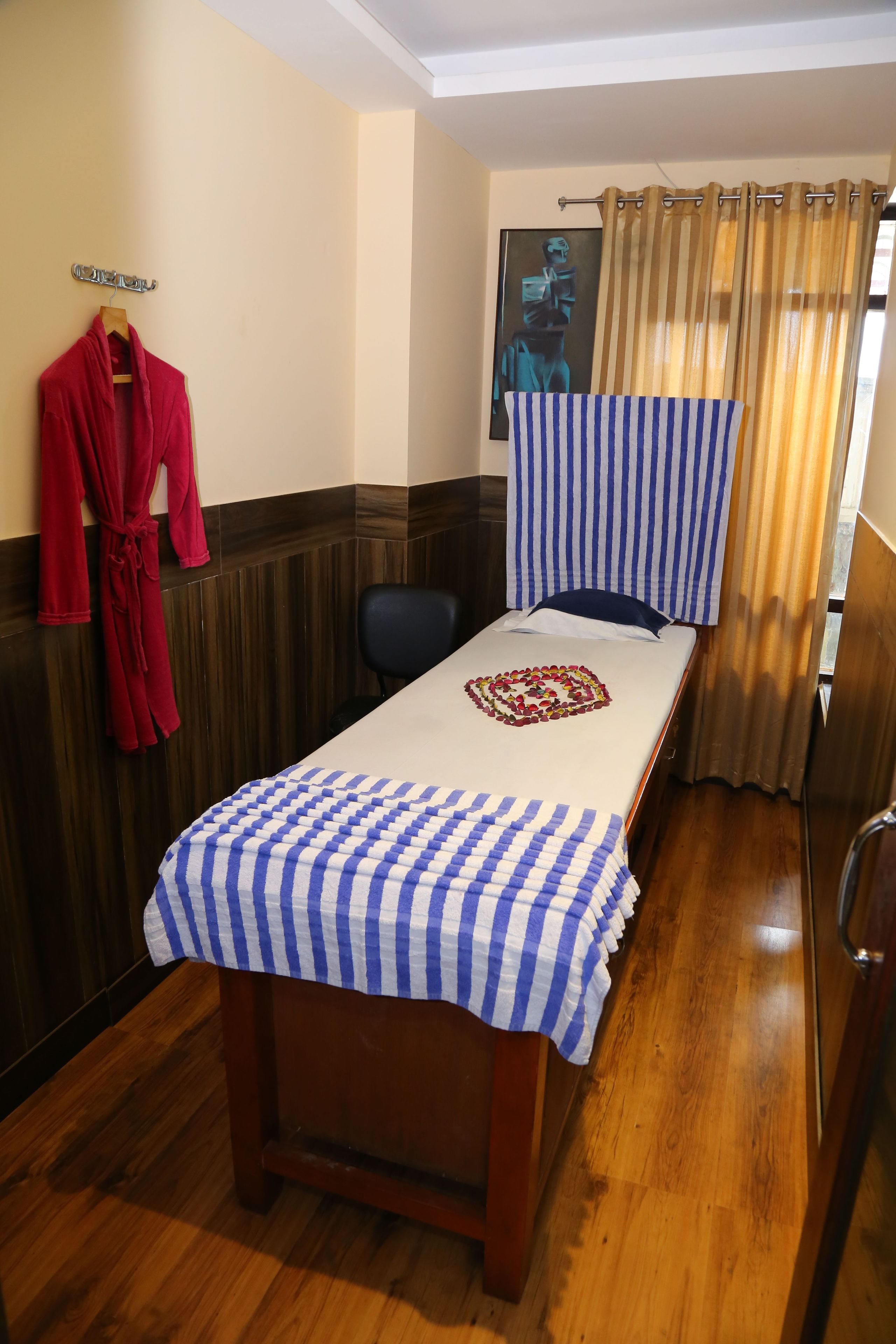 A single bed with a heart-shaped decoration, a red robe hanging on the wall, and a striped headboard.