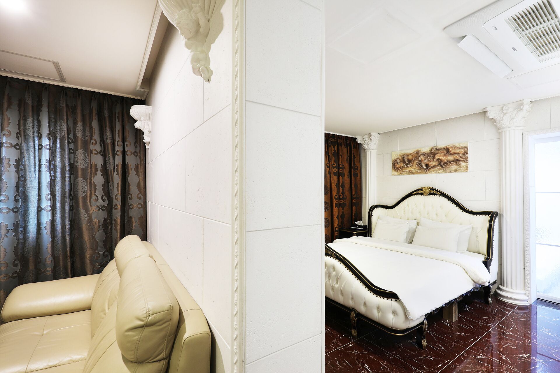 A hotel room with a bed, a chair, and a painting on the wall.