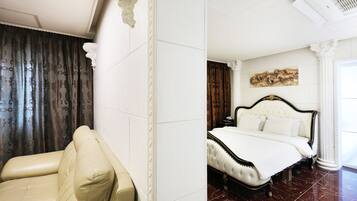 A hotel room with a bed, a chair, and a painting on the wall.