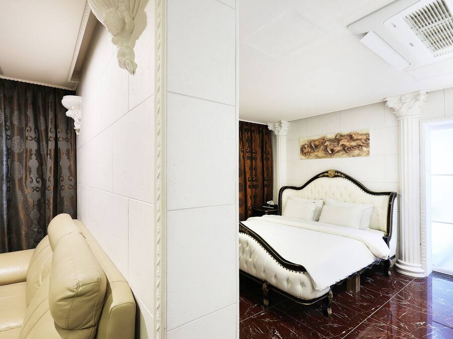 A hotel room with a bed, a chair, and a painting on the wall.