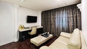 A modern living room with a flat-screen TV, a sofa, a coffee table, and a desk with a chair. - Paju Golden Hill (Paju)
