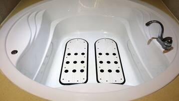Uma banheira branca com dois apoios para os pés e uma torneira.