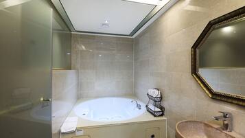 Un baño moderno con una bañera independiente, un tocador con encimera de granito y un espejo grande con un marco ornamentado.