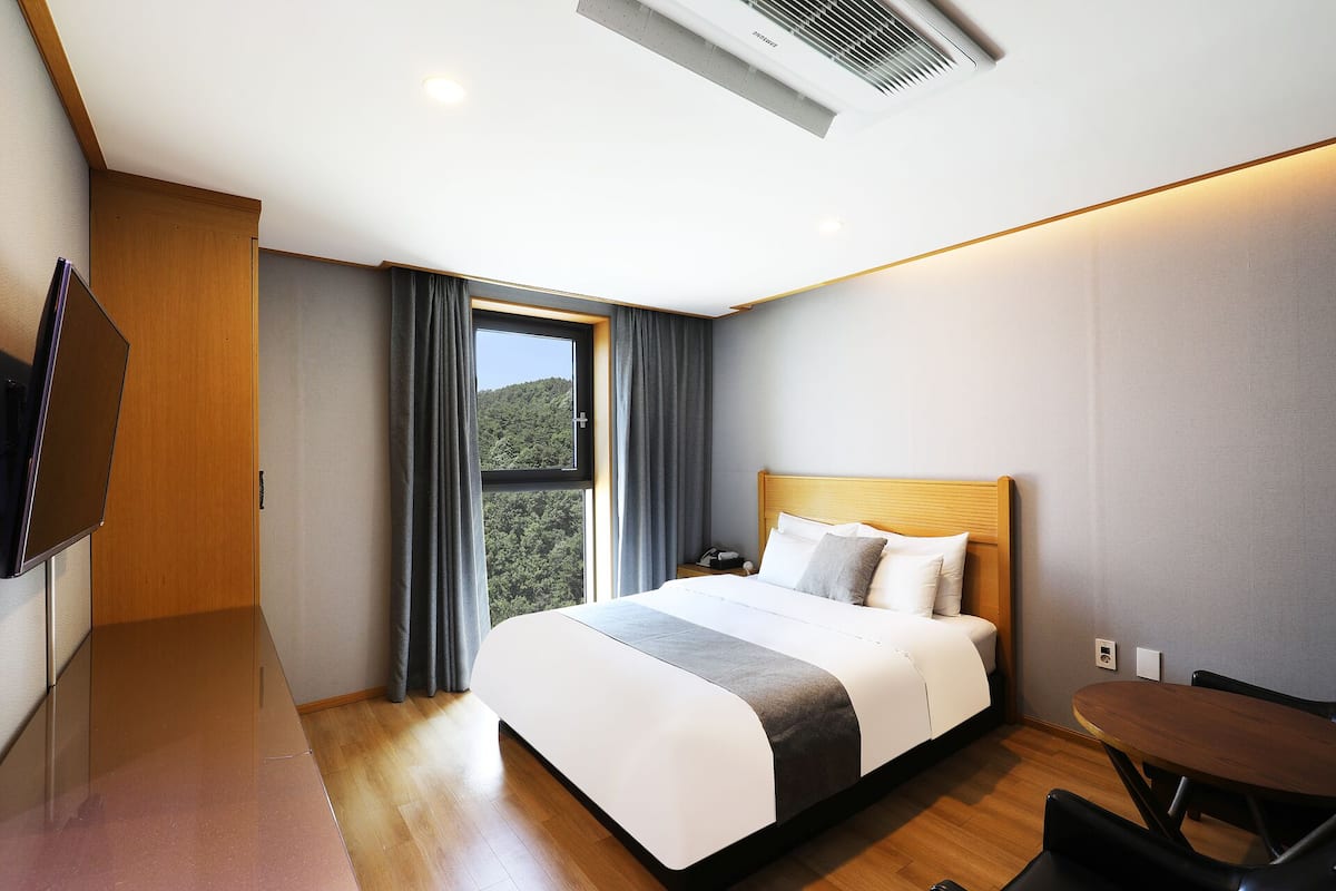 A modern hotel room with a large bed, a desk, and a television.