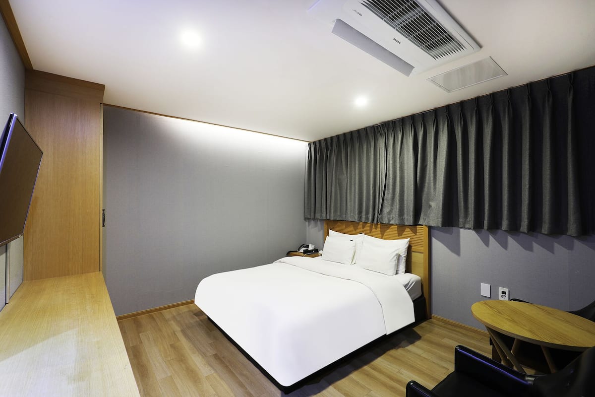 A modern hotel room with a bed, bedside table, and a small round table.